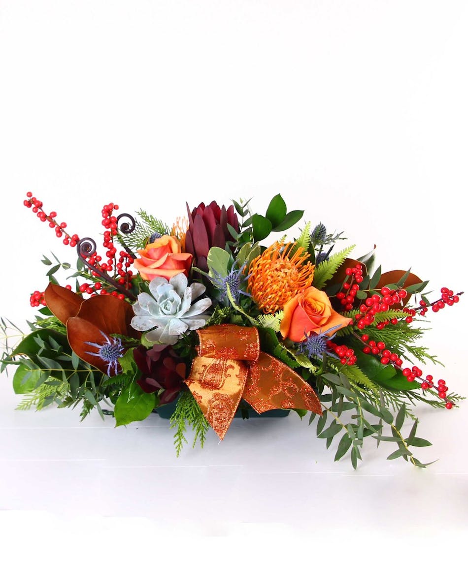 Centerpiece filled with fall flowers and accented with ribbon and succulents.